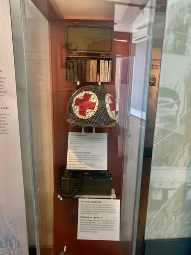 An M-1 WWII helmet with Red Cross and a TP-9 Field Telephone. While most US units were equipped with radios, field telephones often provided more reliable communcations between front line positions and unit headquarters. Laying telephone  wire under fire  was particularly hazardous.