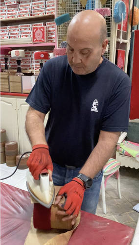 A shop owner in the process of making the ubiquitous red felt hats.